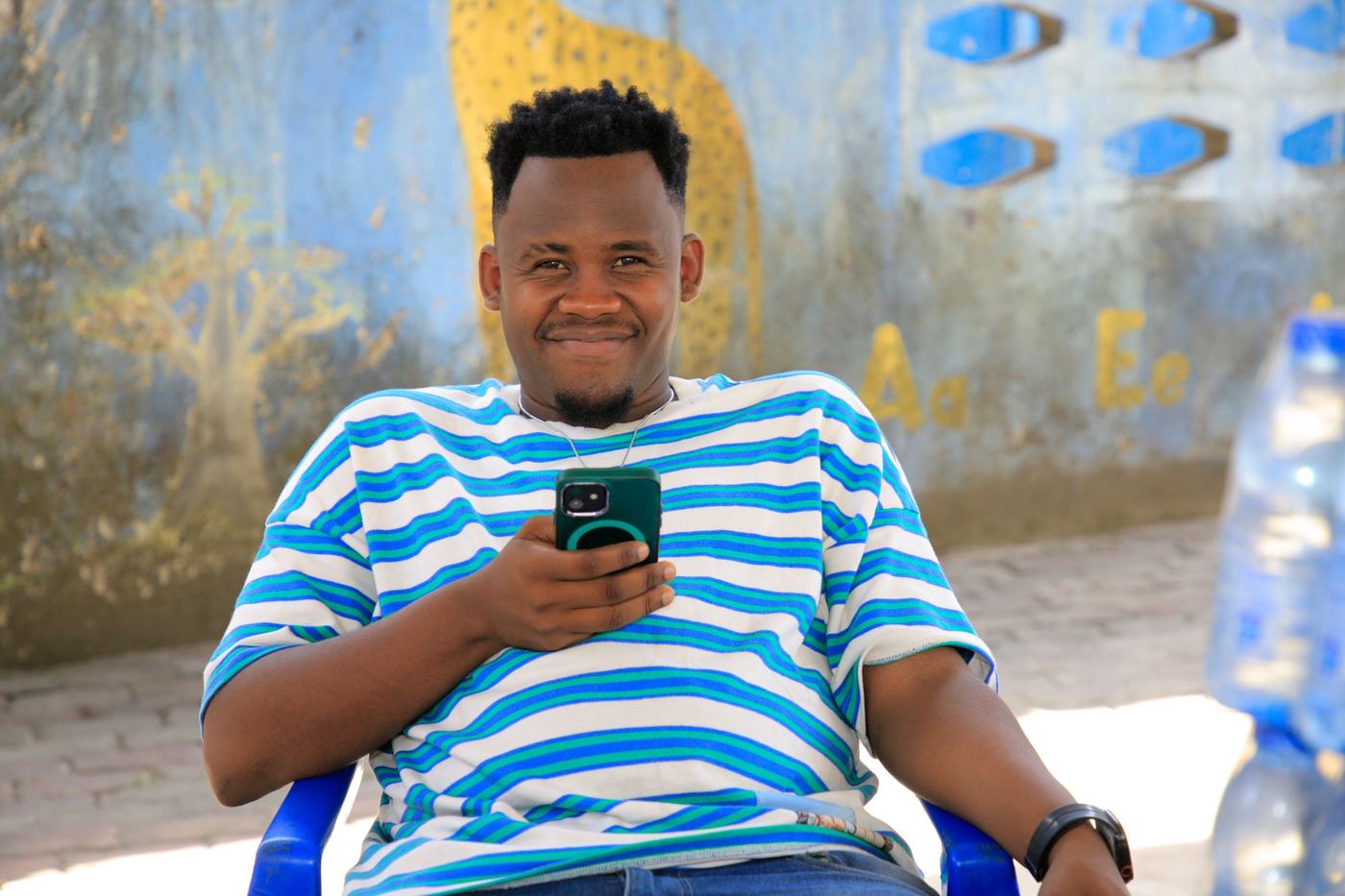 Un jeune homme sourit, son téléphone à la main