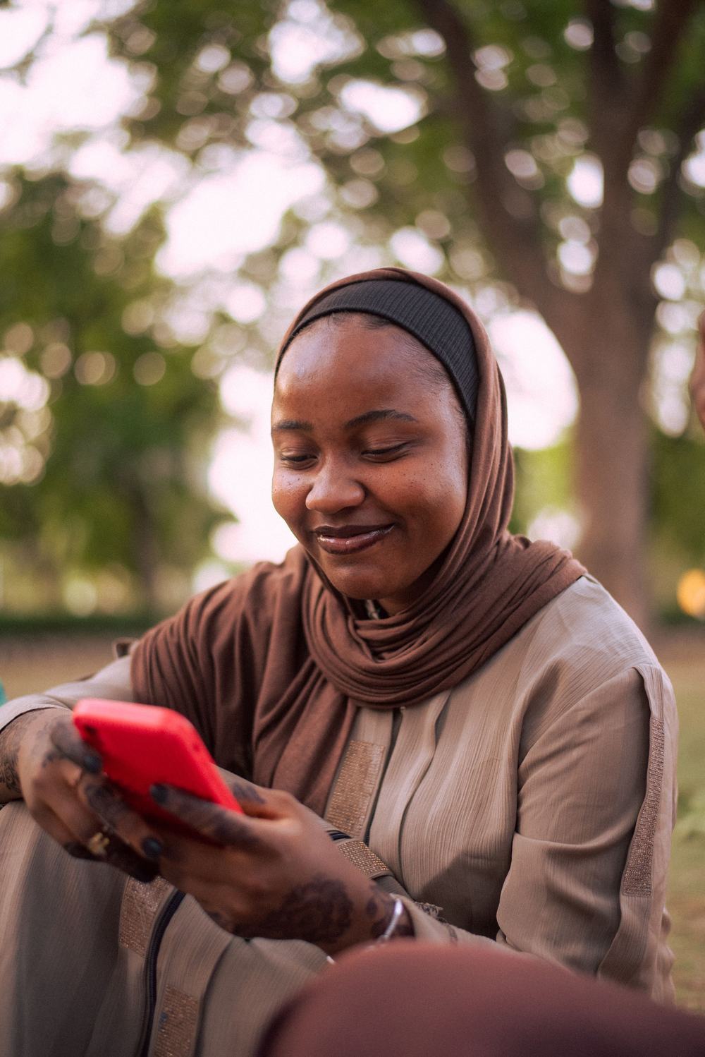 Une jeune femme sourit en regardant son téléphone